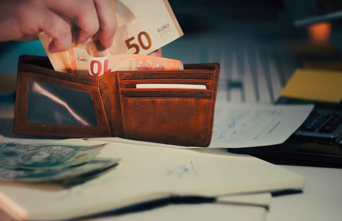Wallet with euro banknotes on a desk with papers